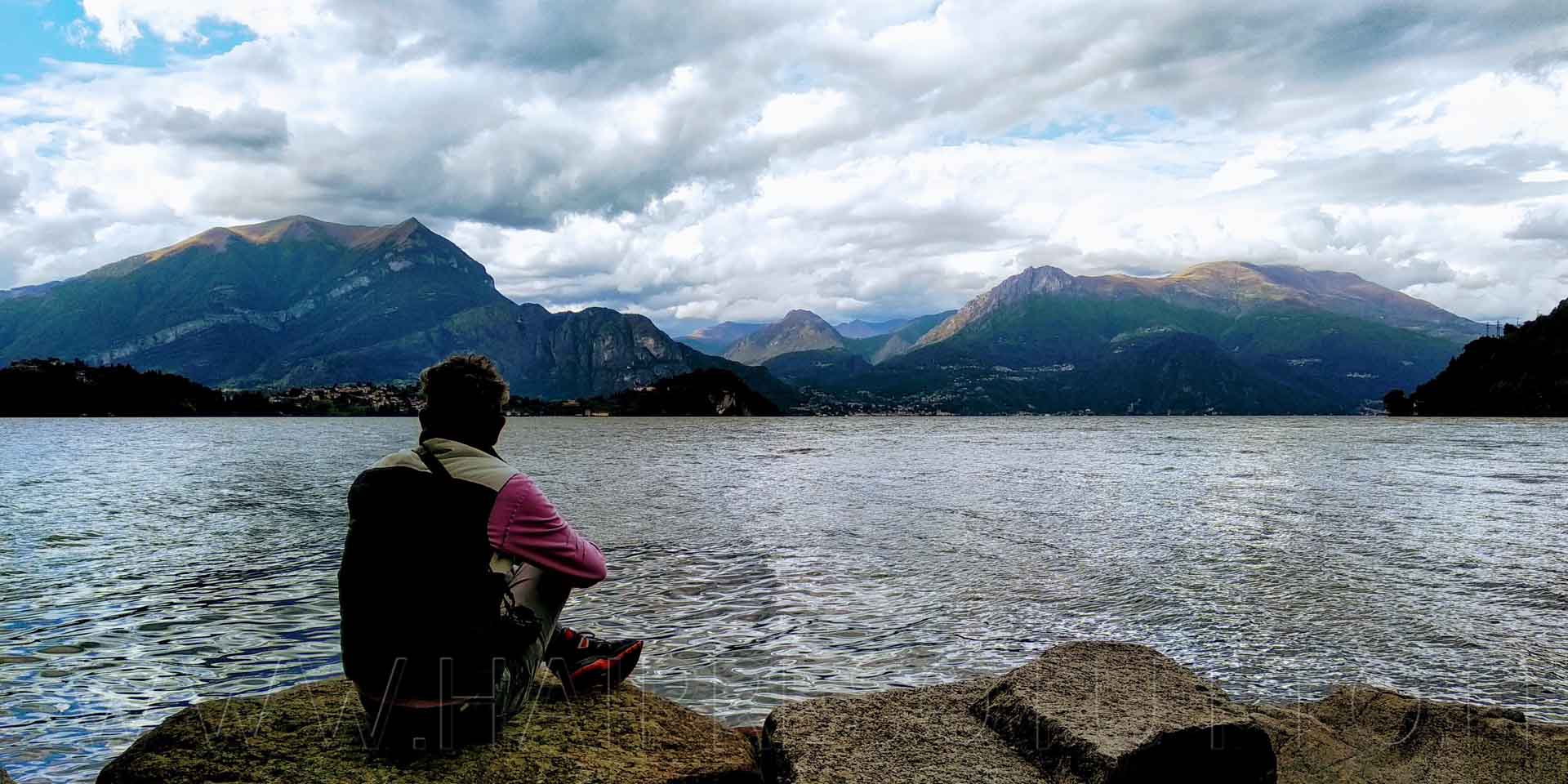 Will seduto sui massi guarda l'orizzonte sulle sponde del lago di Como